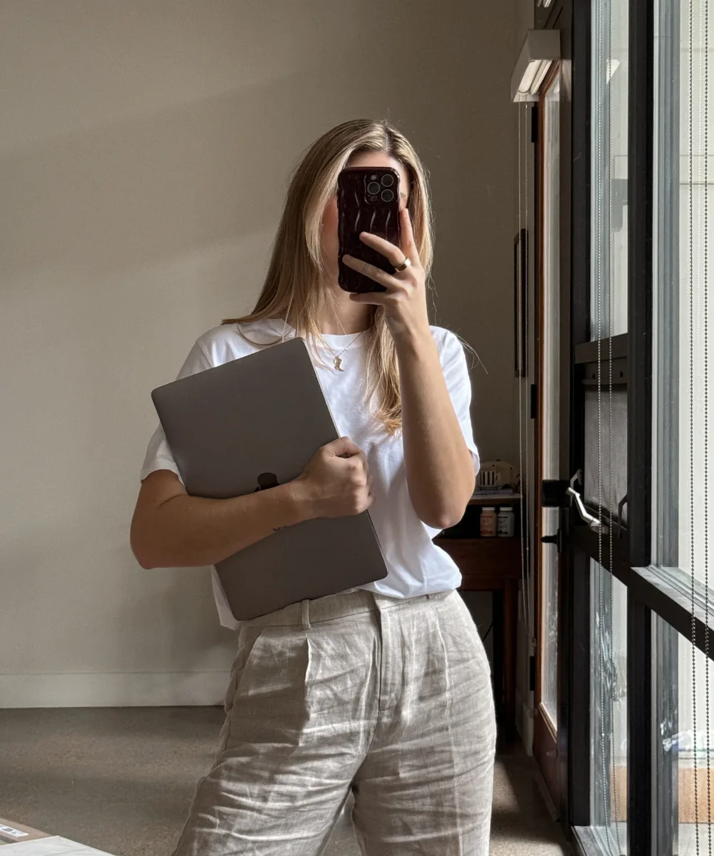 Woman holding a laptop taking a mirror selfie — fill-in-the-blank copywriting templates make writing easy