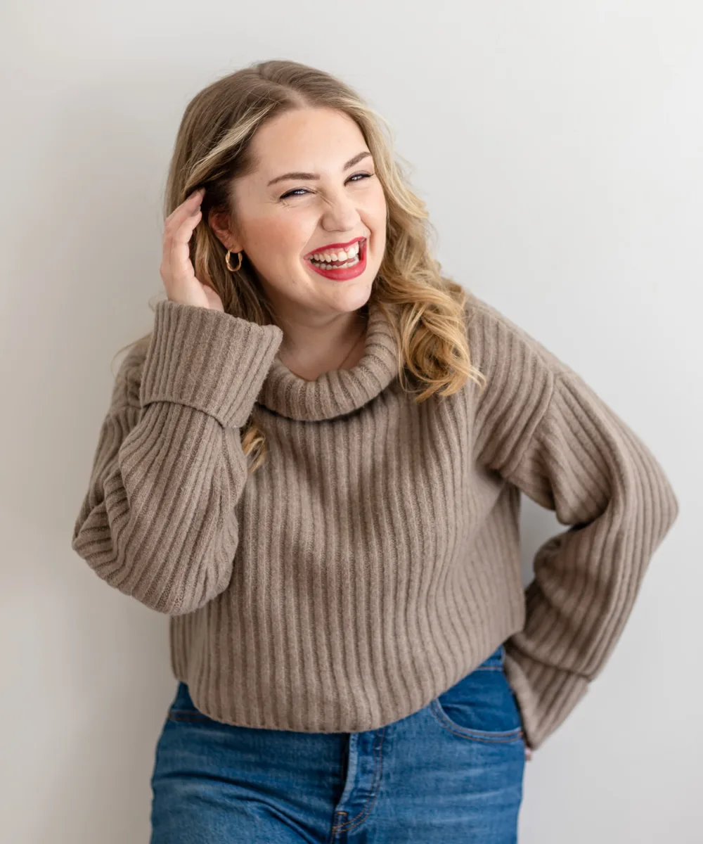 Megan Elliott laughing in a taupe sweater, lifestyle portrait