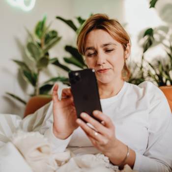 Woman lying on a couch at night scrolling on her phone with a concerned expression, representing how potential clients search for service based businesses on Google