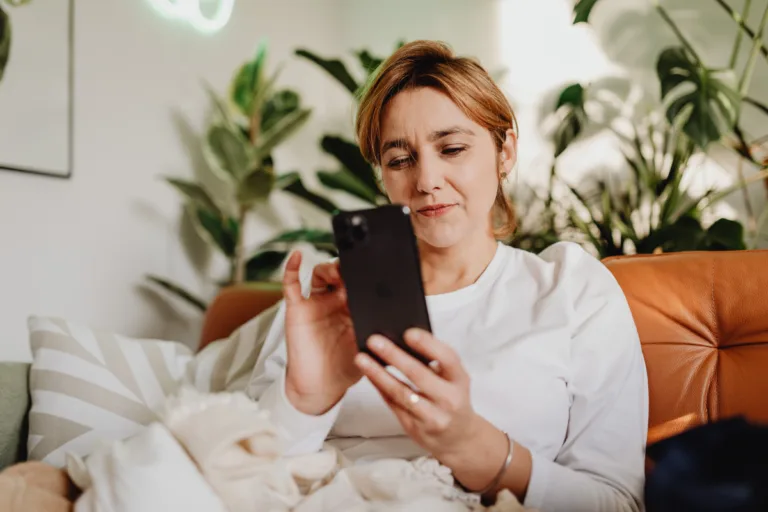 Woman lying on a couch at night scrolling on her phone with a concerned expression, representing how potential clients search for service based businesses on Google