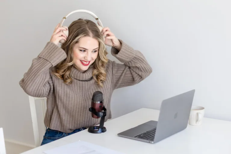 Megan Elliott, copywriter and founder of The Copy Template Shop, smiling while adjusting headphones at her desk with a microphone and laptop
